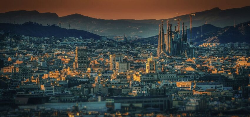 location jet privé : Coucher de soleil sur un paysage urbain avec une cathédrale et des grues proéminentes.