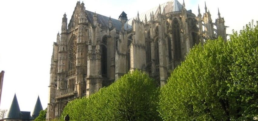 location de jet privé : Cathédrale gothique, arbres et ciel nuageux.