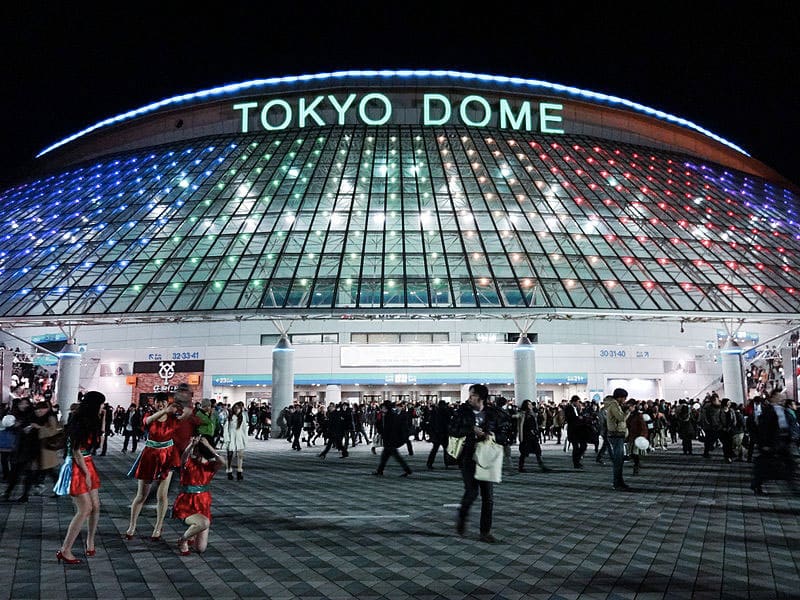 Dôme nocturne illuminé au Tokyo Dome, foule présente.