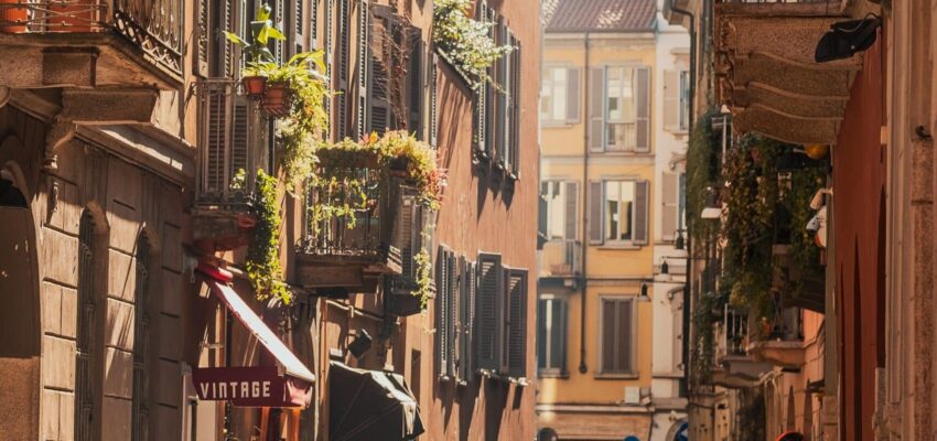 Milan Linate, rue ensoleillée avec motos et balcons.