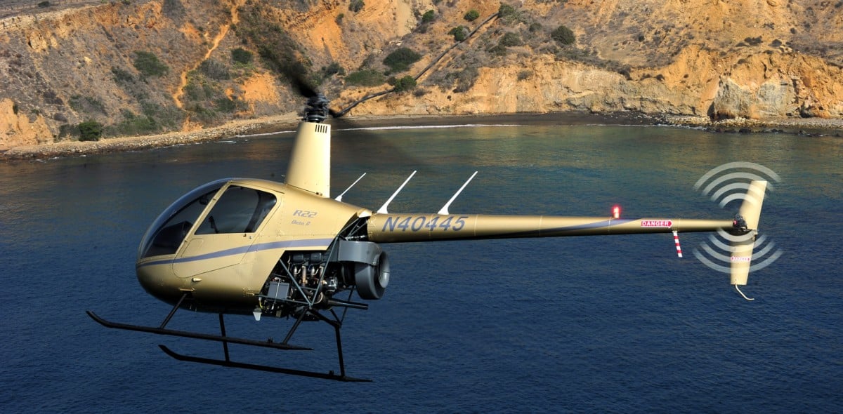 Hélicoptère Robinson R22 gris en vol au-dessus de la mer