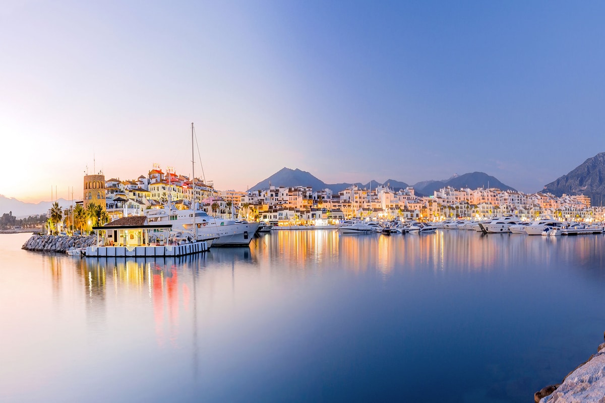 Marina de Puerto Banus au crépuscule, yachts amarrés, toile de fond de montagne.